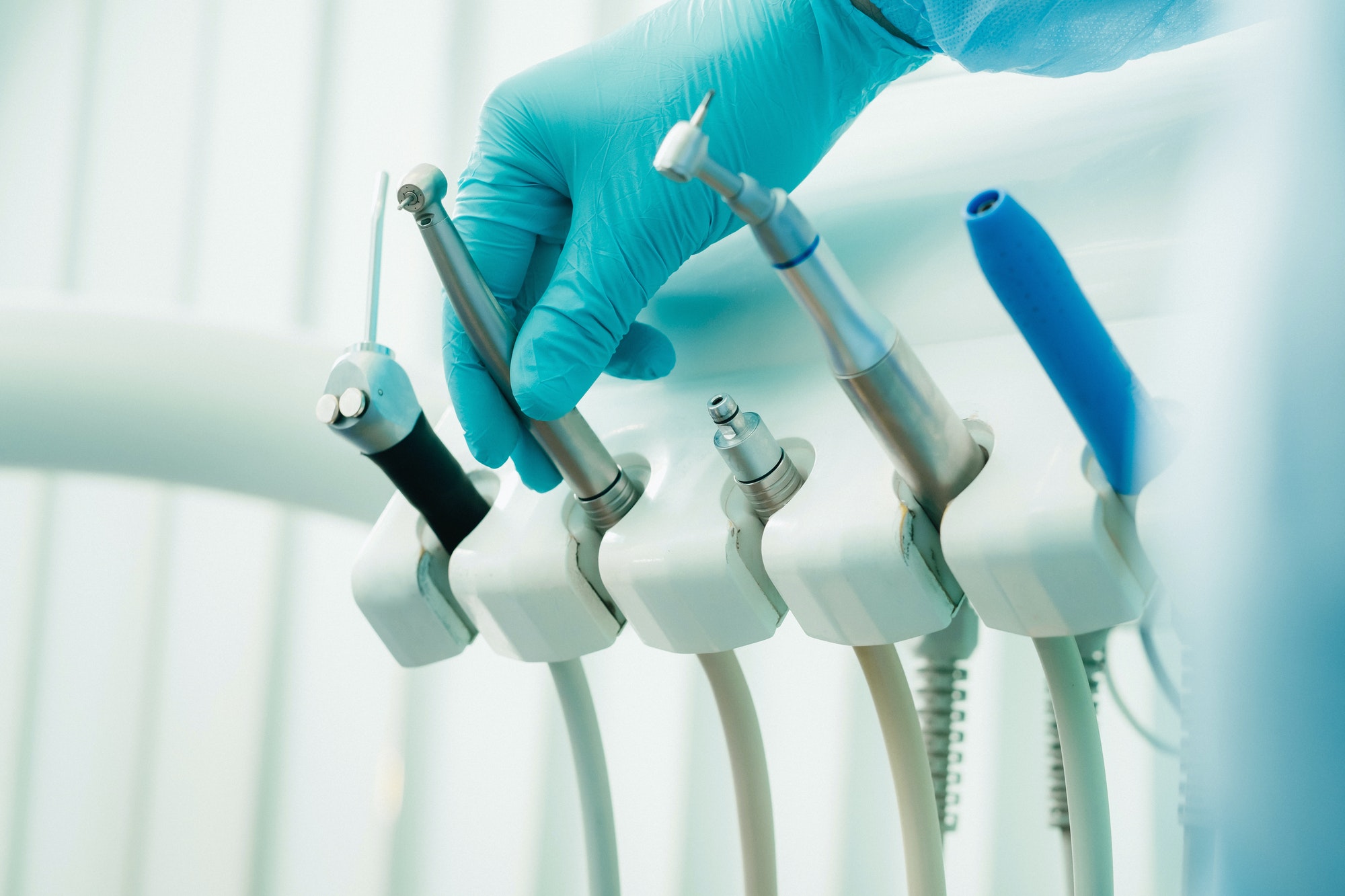 a dentist wearing gloves in the dental office holds a tool before working